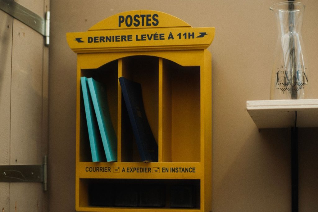 A yellow vintage French wall-mounted post rack with labelled compartments, most of them empty