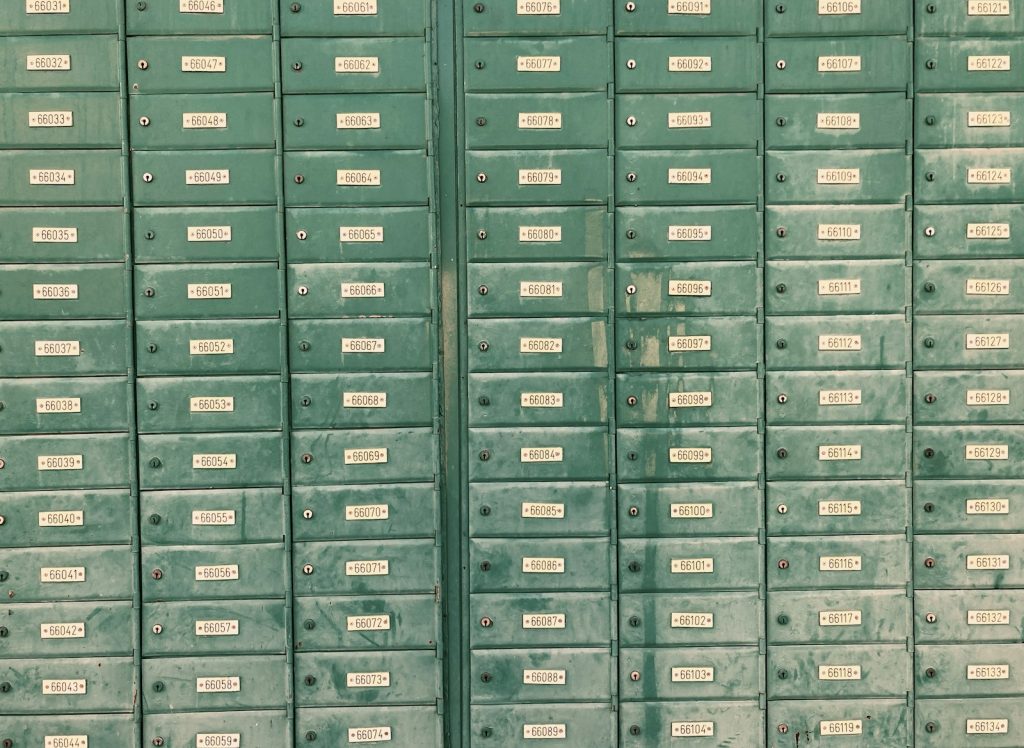 A wall of numbered green mailboxes, all closed, standing in for files nobody ever collects