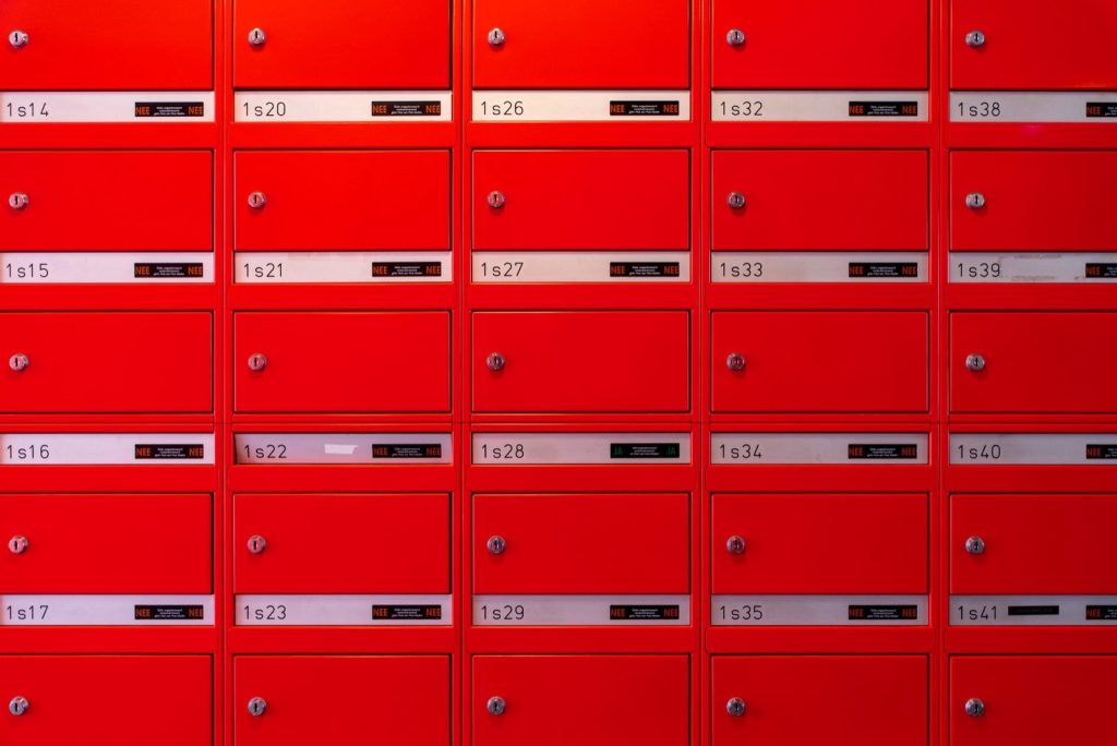 A grid of identical red numbered mailboxes filling a wall