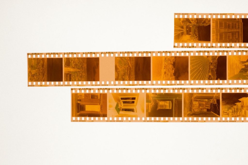 Three strips of orange 35mm film negatives laid out on a white light box