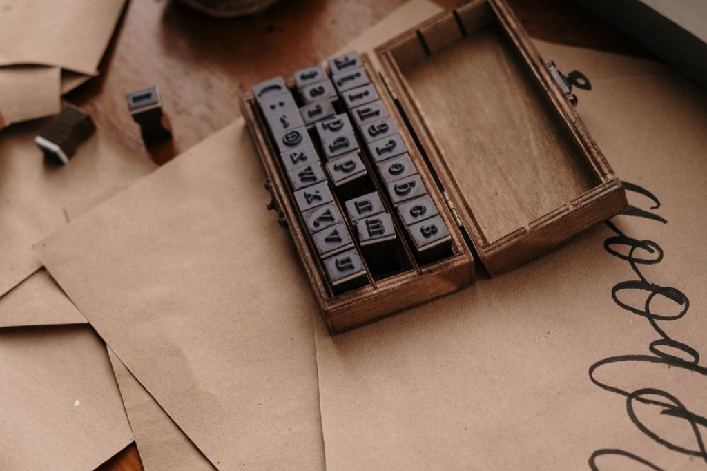 A wooden case of small letterpress type stamps lying open on sheets of kraft paper